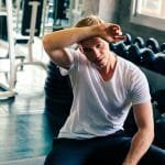 Young man wiping sweat off forehead in gym. Single menn stinker!