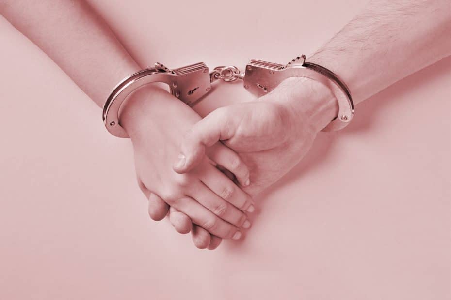 BDSM dikt. Rosa bakgrunn, mannlig og kvinnelig hånd som holder hverandre, og med håndjern rundt hvert håndledd.