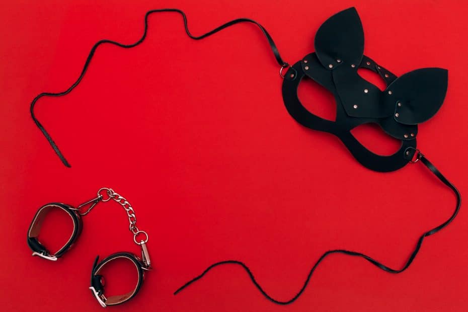 Black leather cat mask on a red background.Concept of Valentine's Day, BDSM communities