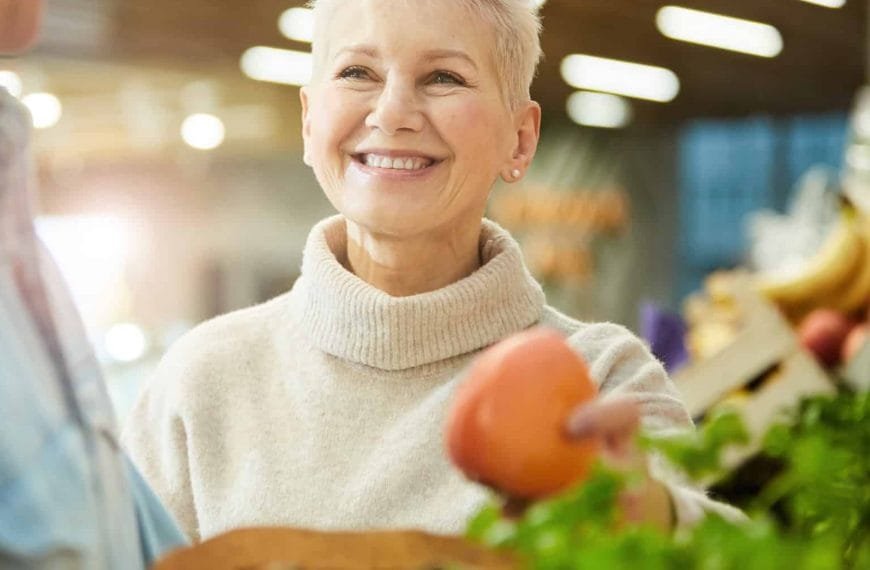 Godt voksen dame handler i grønssaksdisken på en matbutikk som Rema 1000.