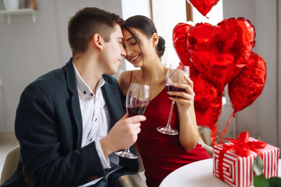Valentinsdagen: Illustrasjon med vakkert par i dress og kjole, drikker vin, flørter, hjerteballonger.