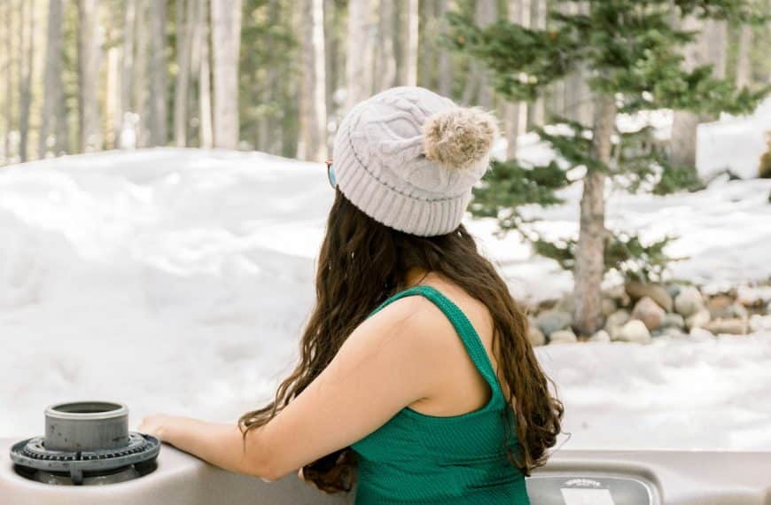 Woman enjoying the day in a hot tub outside a cabin during winter