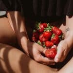 Beautiful Sexy swarthy woman with strawberries in the summer on the balcony. Summer food, fruits, be