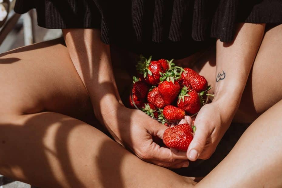 Beautiful Sexy swarthy woman with strawberries in the summer on the balcony. Summer food, fruits, be