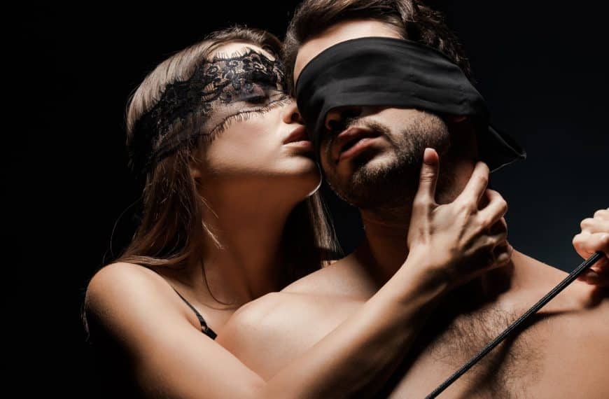 BDSM dame står bak og kjærtegner mann med blindfold