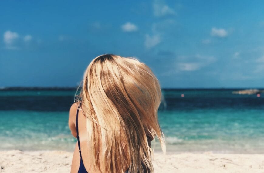 Rear view of blonde woman sitting on the beach