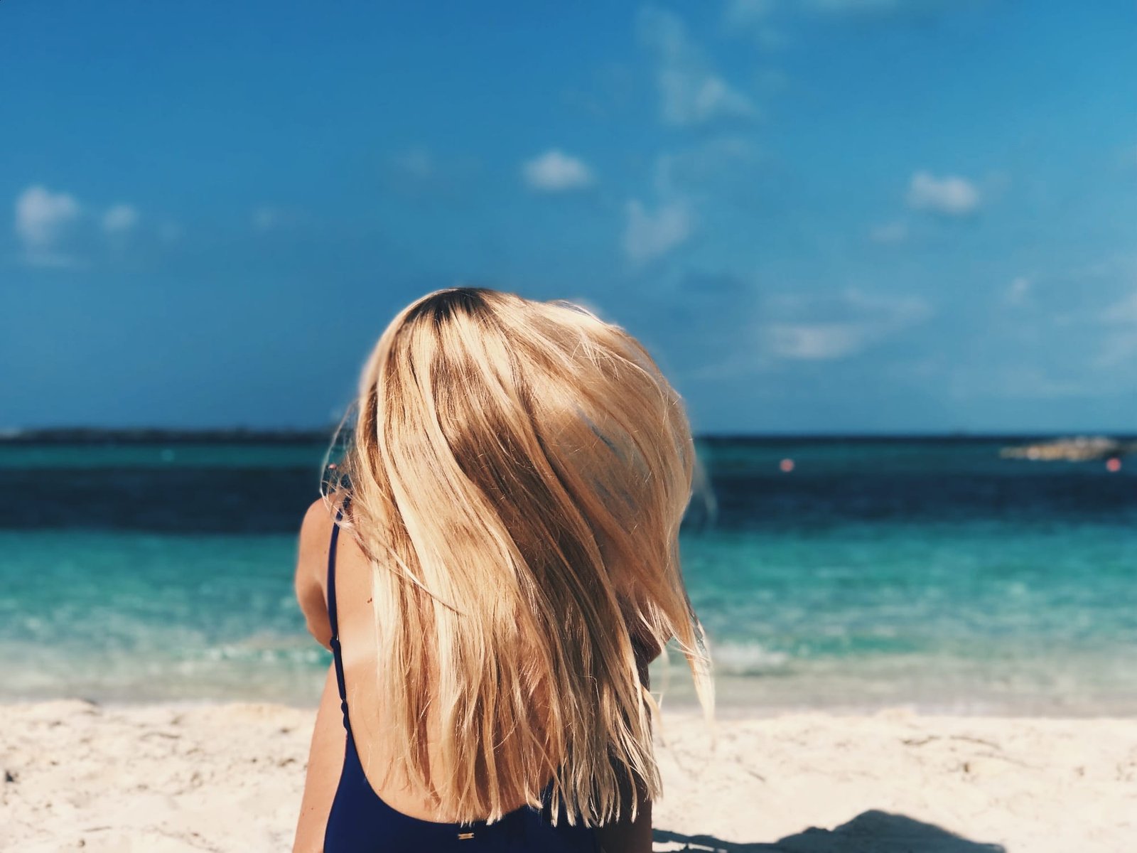 Rear view of blonde woman sitting on the beach