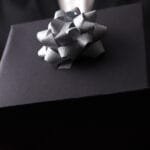 Mann med dress holder en sort gave formet som en boks med sølv sløyfe