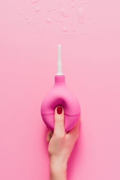Dame holder anal douche på rosa bakgrunn