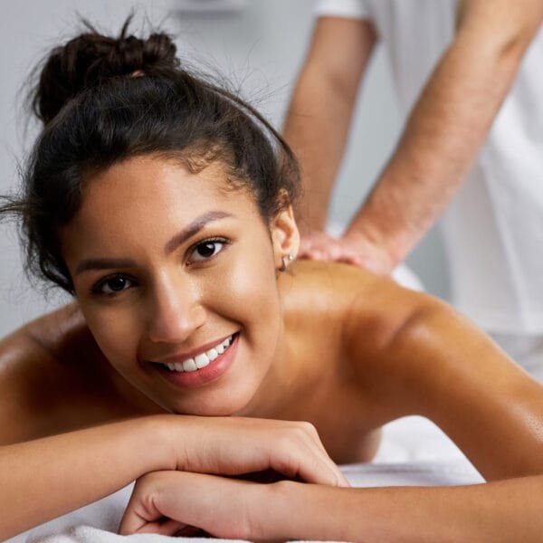 En vakker dame ligger på massasjebenken og mottar massasje fra en mann