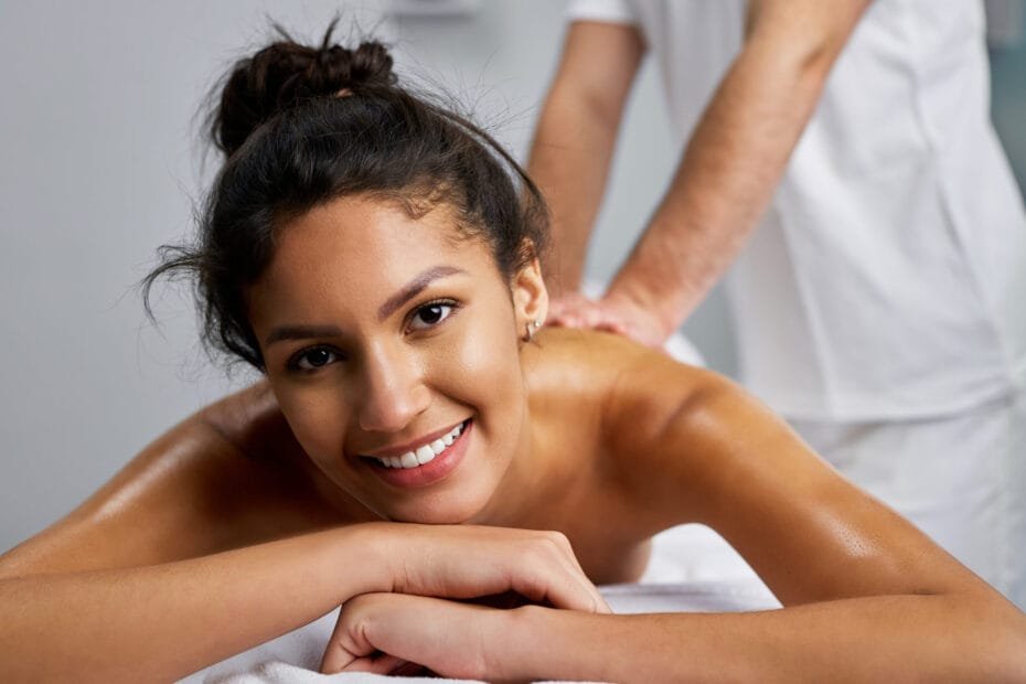 En vakker dame ligger på massasjebenken og mottar massasje fra en mann