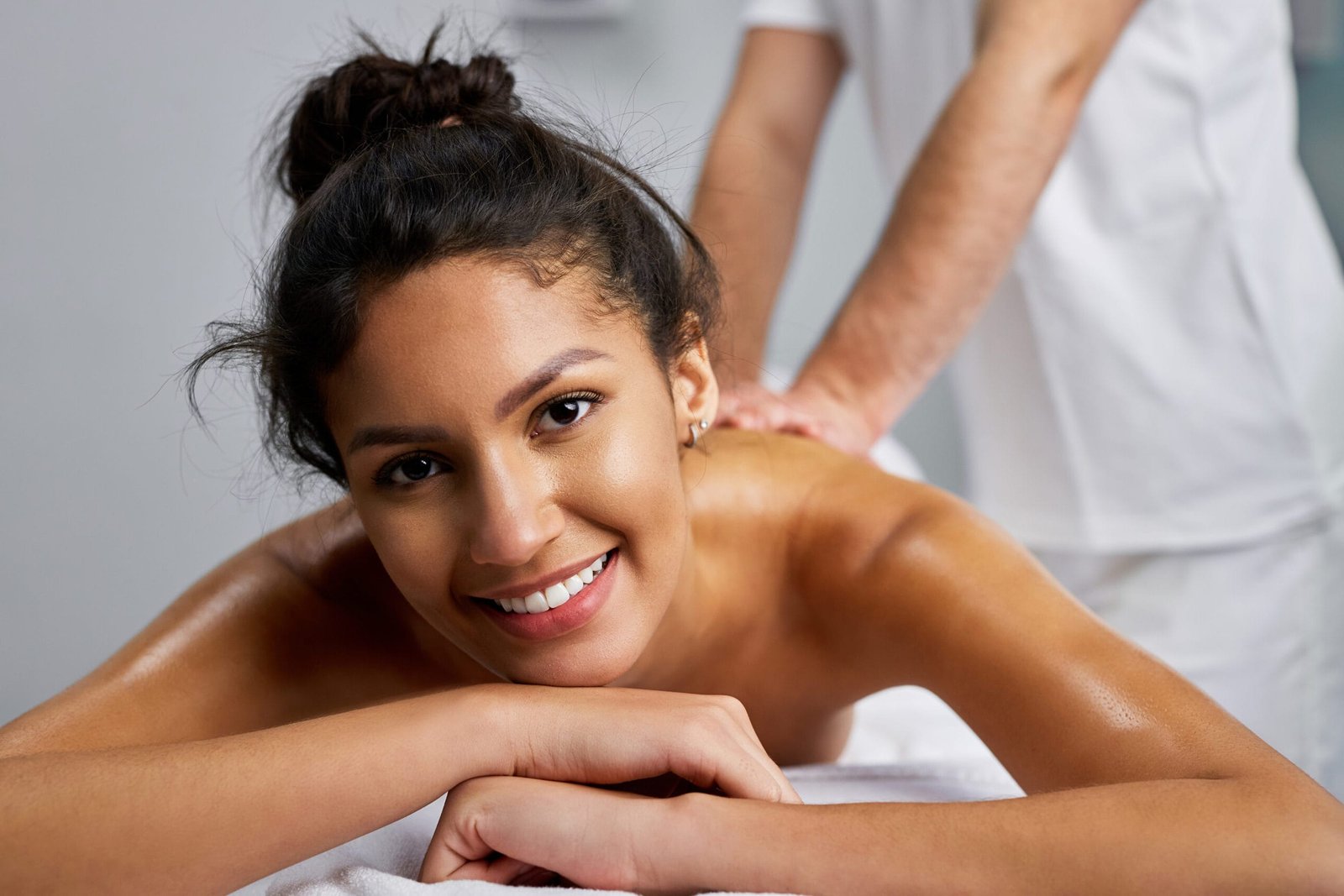 En vakker dame ligger på massasjebenken og mottar massasje fra en mann