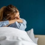 Fortvilt og traumatisert dame sitter i sengen