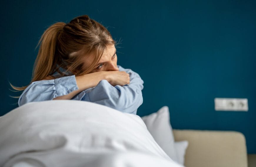 Fortvilt og traumatisert dame sitter i sengen