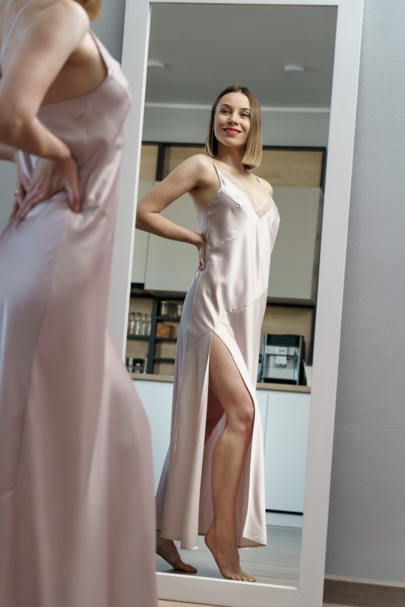 Vakker dame i tynn kjole står og ser seg i et full høyde speil