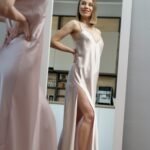 Vakker dame i tynn kjole står og ser seg i et full høyde speil