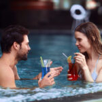 Pen dame og mann i en jacuzzi drikker fargerike drinker