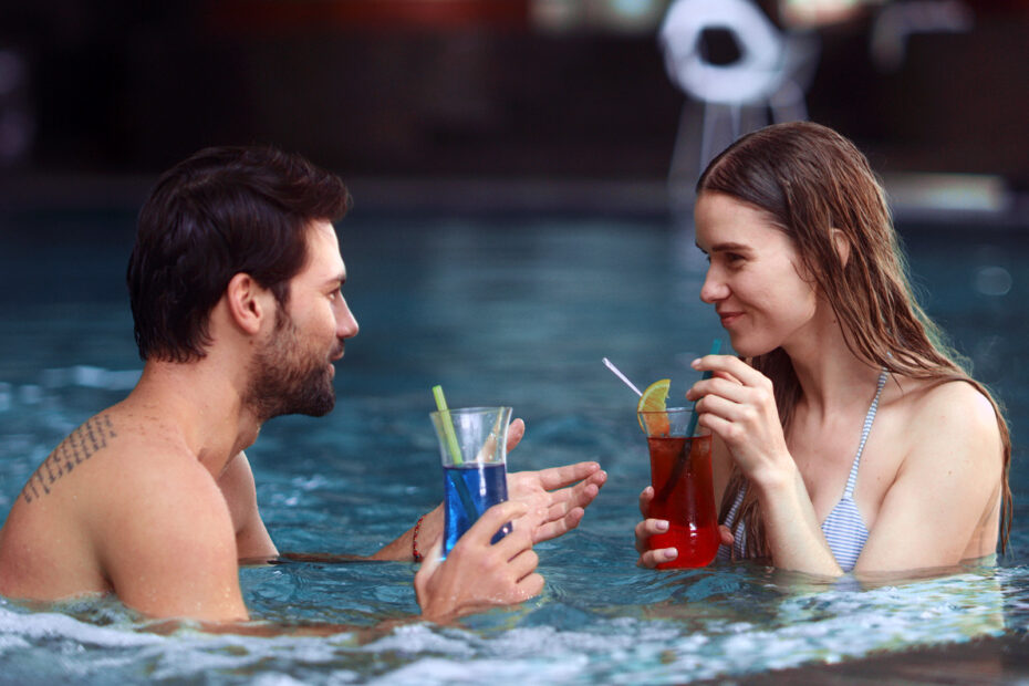 Pen dame og mann i en jacuzzi drikker fargerike drinker