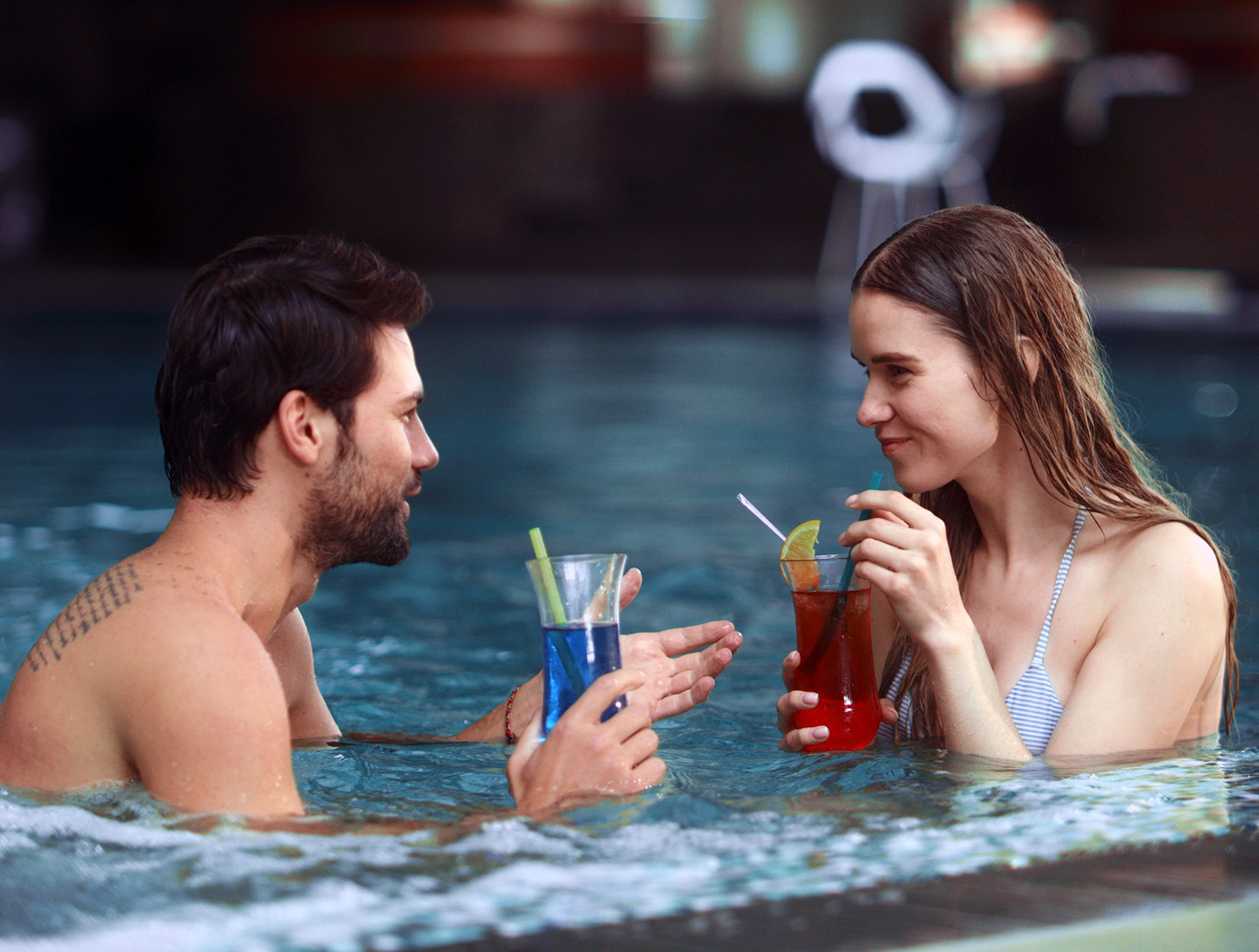 Pen dame og mann i en jacuzzi drikker fargerike drinker